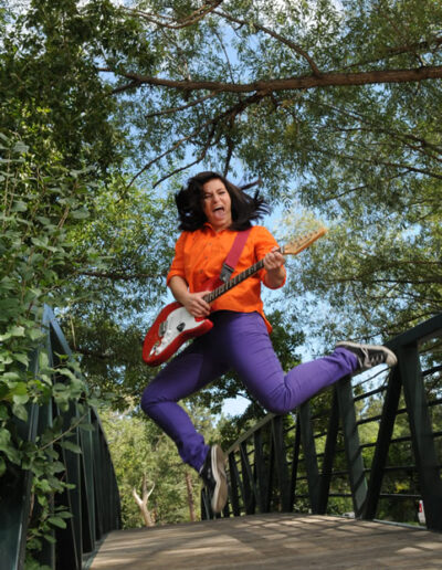 senior photo of girl jumping with guitar