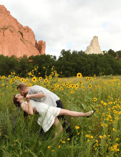 kissing in field of wild flowers and red rocks behind them