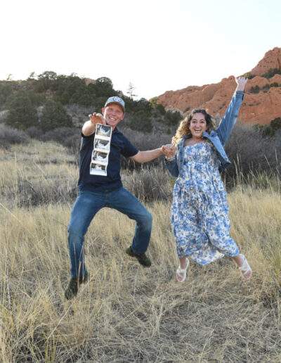 couple jumping with picture of new baby